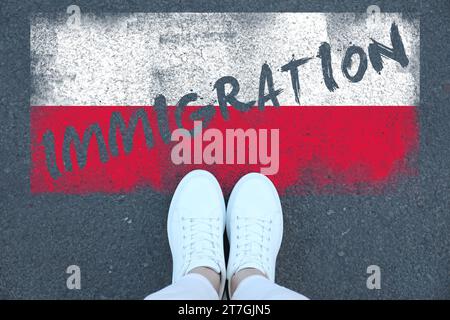 Immigration. Femme debout sur l'asphalte près du drapeau de la Pologne, vue de dessus Banque D'Images