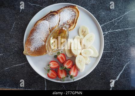 gâteau à la poêle servi avec miel, baies de paille et banane sur une assiette Banque D'Images