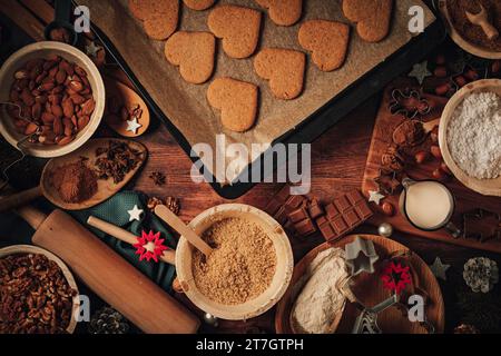 Biscuits de Noël cuits au four sur plaque de cuisson, forme de coeur, ingrédients de cuisson, décorations de Noël, farine, sucre, amandes, noix, cannelle, emporte-pièces Banque D'Images