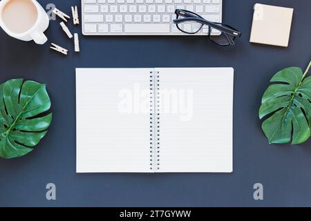 Ordinateur portable ouvert près du bureau de tasse à café avec des feuilles de verre Banque D'Images