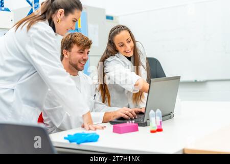 Scientifique pointant l'écran d'un ordinateur portable à côté de collègues dans un laboratoire de recherche Banque D'Images