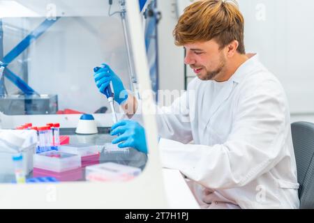 Vue latérale d'un jeune biologiste utilisant une pipette dans un laboratoire innovant Banque D'Images