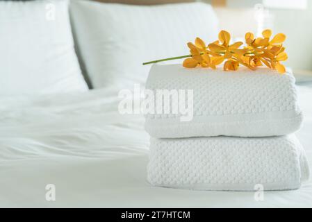 Gros plan, serviette blanche fraîche avec des fleurs placées à l'intérieur de la chambre d'hôtel. Banque D'Images