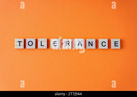 Mot de tolérance. La phrase est disposée en lettres en bois vue de dessus. Fond plat orange Banque D'Images