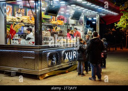 Découvrez l'essence de la vie urbaine de Barcelone : un stand traditionnel de churro dégageant chaleur, arômes tentants et rassemblements animés, au gré des gens Banque D'Images