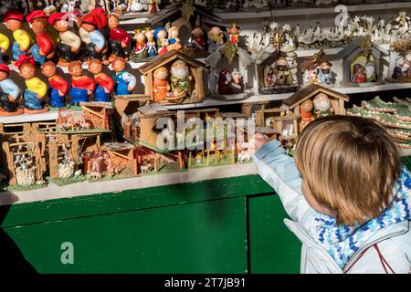 Enchanté par la tradition, un enfant explore les diverses figurines de la nativité – Caganer, animaux de ferme et scènes de nativité – au marché de Noël de Santa Llucia à Banque D'Images