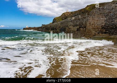 Vue sur la mer des vagues et le mur du port avec vue sur la cabane et le rivage houle au début de l'été. Plage de Portreath, Cornwall. Banque D'Images