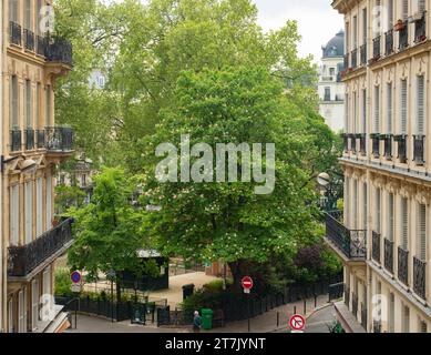 Paris, France - 8 mai 2023 : de grands arbres entre des immeubles historiques au Square Montholon. Banque D'Images