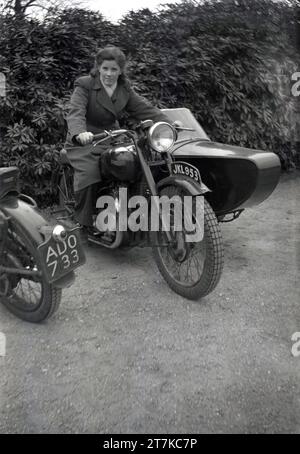 Années 1950, historique, une jeune femme assise sur une moto Triumph de l'époque, avec side-car attaché, Oldham, Manchester, Angleterre, ROYAUME-UNI. Banque D'Images
