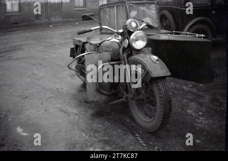 Années 1950, historique, une moto et side-car Harley Davidson fabriqués aux États-Unis garés dans une ruelle latérale, Oldham, Angleterre, Royaume-Uni. La moto vue est peut-être une WL, un modèle d'avant la seconde Guerre mondiale. Le design du sidecar est intéressant, ressemblant à un petit bateau avec toit fermé. Banque D'Images