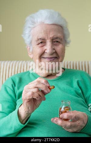 une belle femme âgée tenant la capsule de vitamine et son pot Banque D'Images