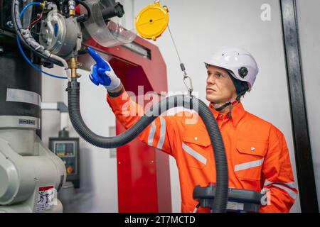 Mécanicien d'ingénieurs utilisant le bras robotique de contrôleur d'ordinateur pour souder l'acier dans l'atelier d'usine d'acier. Logiciel de programmation de robot industriel pour automate Banque D'Images