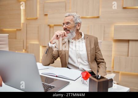 agent immobilier heureux avec tatouage donnant consultation en ligne par ordinateur portable dans le bureau, chat vidéo Banque D'Images