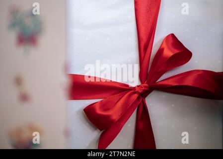 Sous un sapin de Noël moderne, des boîtes-cadeaux élégamment enveloppées de blanc améliorent l'ambiance de vacances dans une maison, aux côtés d'ornements de Noël de vacances, comme un desig Banque D'Images
