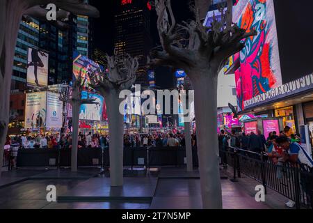 Les gens marchent dans la nuit à Times Square, avec une lueur vibrante de panneaux LED, gratte-ciel imposants, boutiques et paysage urbain animé de Broadway Banque D'Images