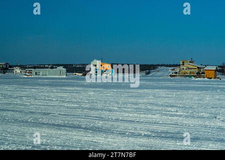 Aperçu du lac des esclaves gelé avec des péniches gelées sur la glace où les habitants vivent toute l'année accédant à leurs maisons en motoneige ou en voiture en hiver mont Banque D'Images