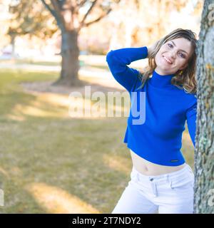 Jeune femme debout portant bleu col roulé manches longues Crop Top blanc denim Jeans Park Banque D'Images