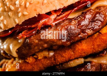 Double hamburger avec bacon grillé fromage jaune oignons tomates concombres et laitue. Résumé de la restauration rapide. Banque D'Images