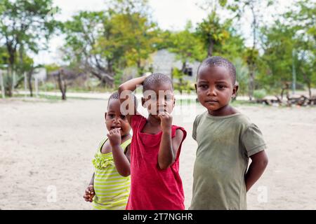 famille trois enfants, en face de la maison dans la cour arrière de sable dans un village en afrique Banque D'Images