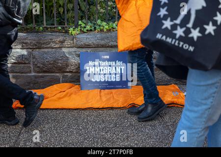 NEW YORK, NEW YORK - NOVEMBRE 16 : un panneau de justice pour immigrants repose sur un sac de couchage alors que les défenseurs des immigrants et leurs alliés organisent un rassemblement et « dorment » devant Gracie Mansion, résidence officielle du maire de New York Eric Adams, l'exhortant à cesser d'attaquer la politique de droit au logement de la ville le 16 novembre 2023 à New York. L'administration Adam a limité les séjours en refuge pour les familles immigrées et a récemment annoncé qu'elle commencerait à distribuer des tentes aux demandeurs d'asile nouvellement arrivés, au lieu d'offrir un hébergement. (Photo de Michael Nigro/Sipa USA) Banque D'Images