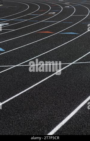 La surface noire et les marquages de voie sur une piste de sport nouvellement installée, fabriquée à partir de pneus recyclés. Banque D'Images