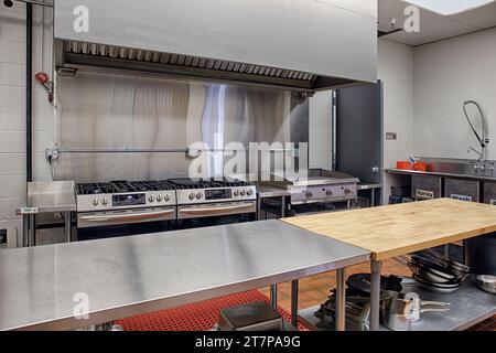 Une cuisine commerciale moderne en acier inoxydable, avec zone de préparation, grill, grillades, gamme, grille-pain, micro-ondes et extincteur. Banque D'Images