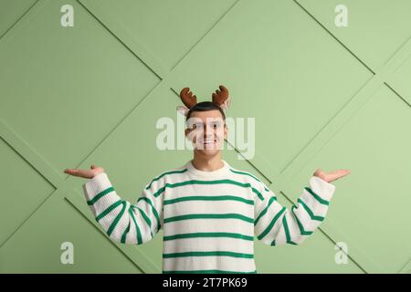 Heureux jeune homme en cornes de renne sur fond vert Banque D'Images