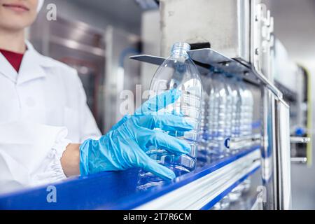 Les travailleuses travaillant dans l'usine d'hygiène dans la production de bouteilles en plastique PET d'eau potable de ligne propre Banque D'Images