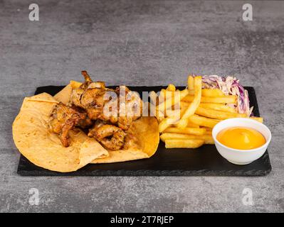 Poulet kebab avec légumes, frites et sauce sur lavash Banque D'Images