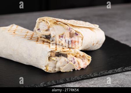 Délicieux shawarma au poulet avec sauce au fromage, légumes, champignons et frites sur une planche à découper Banque D'Images