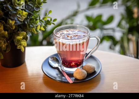 Infusion de thé chaud servie dans une tasse en verre servie avec des biscuits Banque D'Images