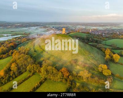 Glastonbury, Somerset, Royaume-Uni. 17 novembre 2023. UK Météo. Couleurs d'automne sur les arbres à Glastonbury Tor à Glastonbury dans le Somerset par un matin clair et froid avec une brume légère peu après le lever du soleil. Crédit photo : Graham Hunt/Alamy Live News Banque D'Images