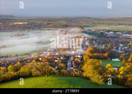 Glastonbury, Somerset, Royaume-Uni. 17 novembre 2023. UK Météo. Les couleurs d'automne sur les arbres tandis que la brume envahit les maisons de Glastonbury dans le Somerset par un matin clair et froid peu après le lever du soleil. Crédit photo : Graham Hunt/Alamy Live News Banque D'Images