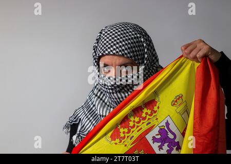 Femme aux yeux verts avec foulard palestinien portant un drapeau espagnol. Concept de conflit Banque D'Images