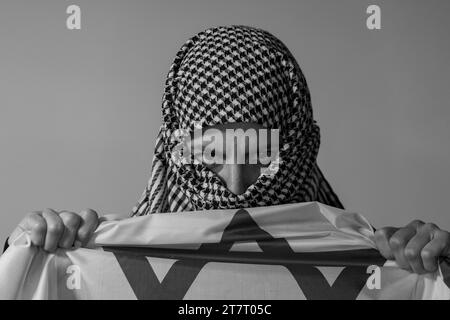 Femme aux yeux verts avec foulard palestinien portant un drapeau israélien. Concept de conflit Banque D'Images