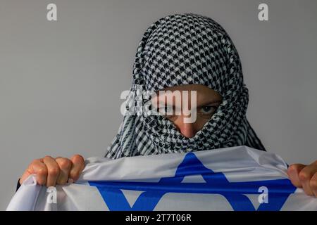 Femme aux yeux verts avec foulard palestinien portant un drapeau israélien. Concept de conflit Banque D'Images