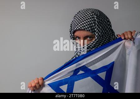 Femme aux yeux verts avec foulard palestinien portant un drapeau israélien. Concept de conflit Banque D'Images