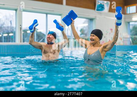 Couple senior sportif faisant des exercices dans la piscine couverte. Photo de haute qualité Banque D'Images