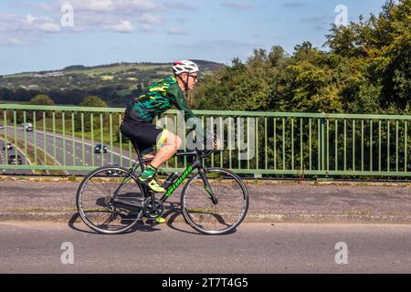 Cycliste de sport spécialisé en fibre de carbone sur la route de campagne traversant le pont autoroutier dans la campagne du Lancashire, Royaume-Uni Banque D'Images