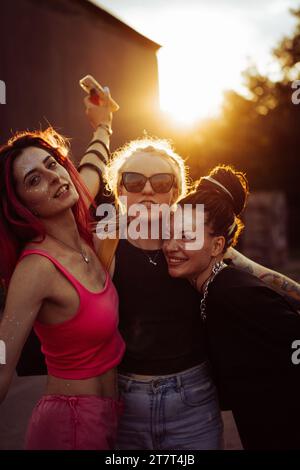 Trois amies heureuses au coucher du soleil, portrait émotionnel, amitié. Banque D'Images