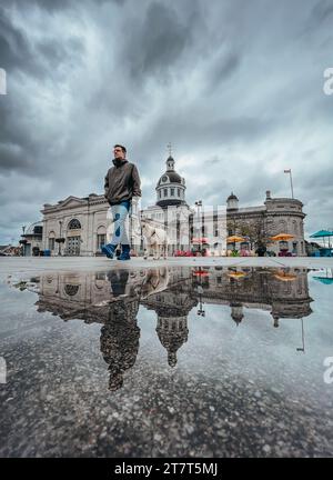 Homme marchant chien le jour de pluie dans la place avec le bâtiment en arrière-plan. Banque D'Images