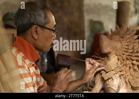 Un homme sculpte une statue en bois dans un atelier. Sculpture sur bois Bali. Banque D'Images