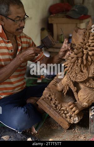 Un homme sculpte une statue en bois dans un atelier. Sculpture sur bois Bali. Banque D'Images