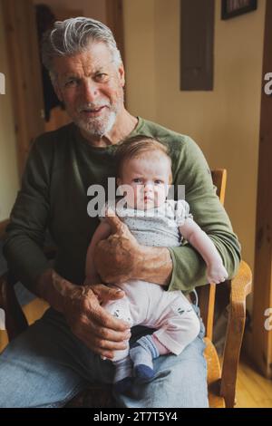 Grand-père souriant tenant la petite-fille Serious Baby Banque D'Images