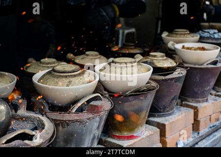 Pots traditionnels en argile sur des poêles à charbon de bois enflammés à Heun Kee Claypot Chicken Rice — Jalan Yew, Pudu ; Kuala Lumpur, Malaisie Banque D'Images