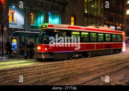 Toronto, Canada - 14 décembre 2013 : vieux tramway ou tramway d'époque roulant dans une tempête hivernale la nuit dans le quartier du centre-ville. Banque D'Images