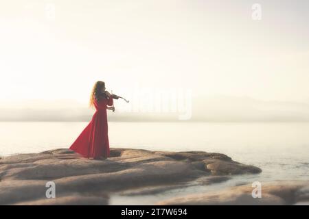 femme à la robe rouge joue du violon dans une atmosphère enchantée Banque D'Images