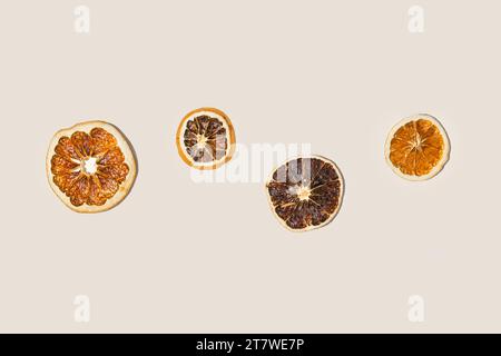 Un ensemble de tranches d'orange séchées isolées sur une couleur beige. Vue de dessus, pose à plat, espace de copie. Toile de fond neutre tendance. Fond de nourriture créative moderne. Mini Banque D'Images