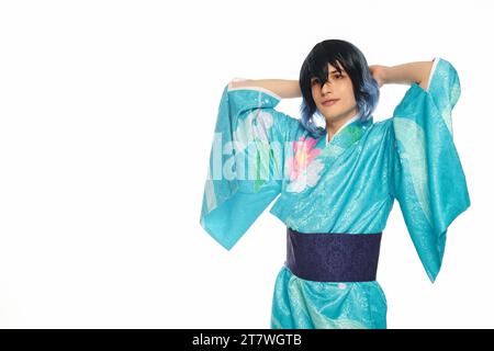 jeune homme en kimono bleu avec les mains derrière la tête regardant la caméra sur blanc, cosplayer rêveur Banque D'Images