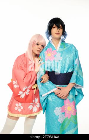 femme blonde de style anime se penchant sur l'homme extravagant en kimono coloré sur blanc, personnages cosplay Banque D'Images